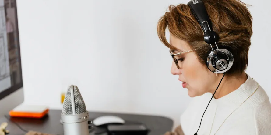 Seated woman wearing headphones talking to a microphone