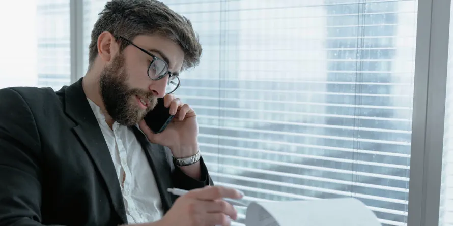 Man speaking on the phone while looking through a document