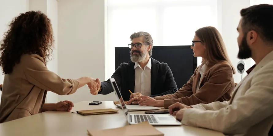 A woman and a man shaking hands over a table