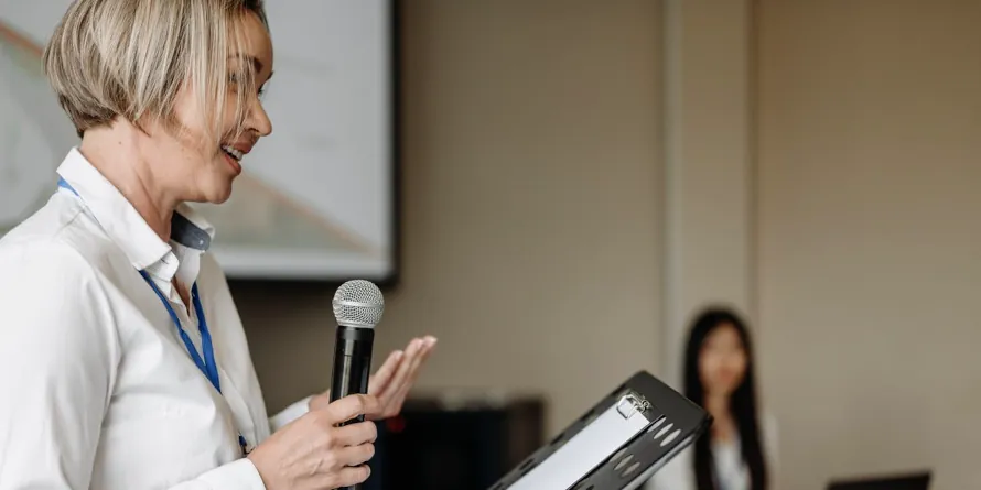 A woman speaking with a microphone at a presentation.