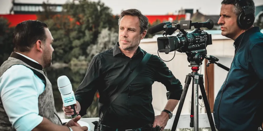 A male journalist and camerman interviewing a man